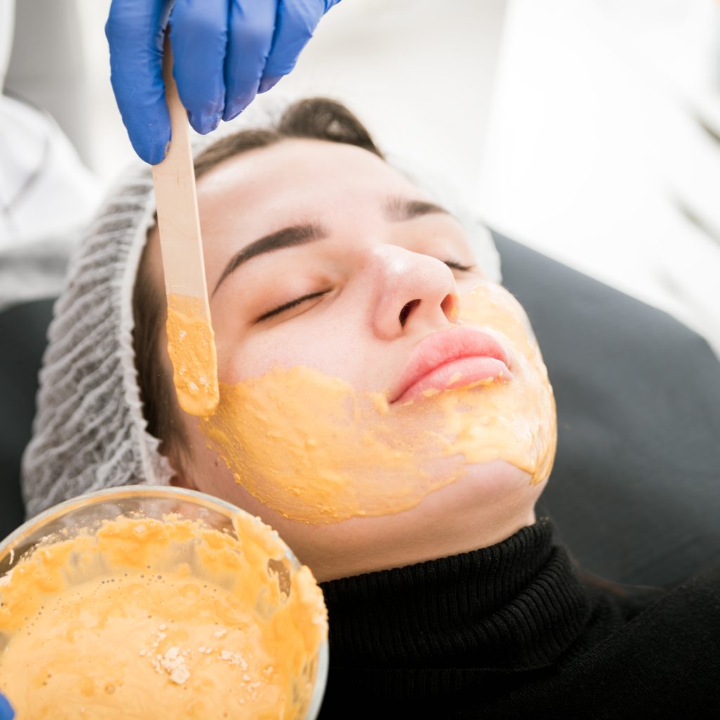 Beautician applying facial mask at cosmetic clinic, cosmetology treatment skincare face